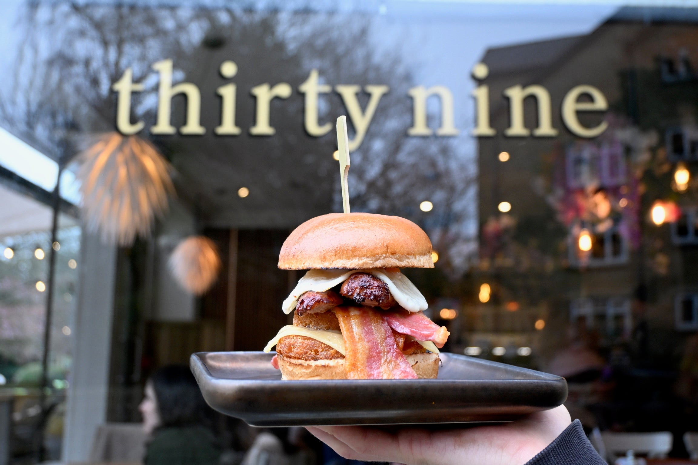 A sausage, bacon and egg sandwich in front of a window branded Thirty Nine Coffee Co
