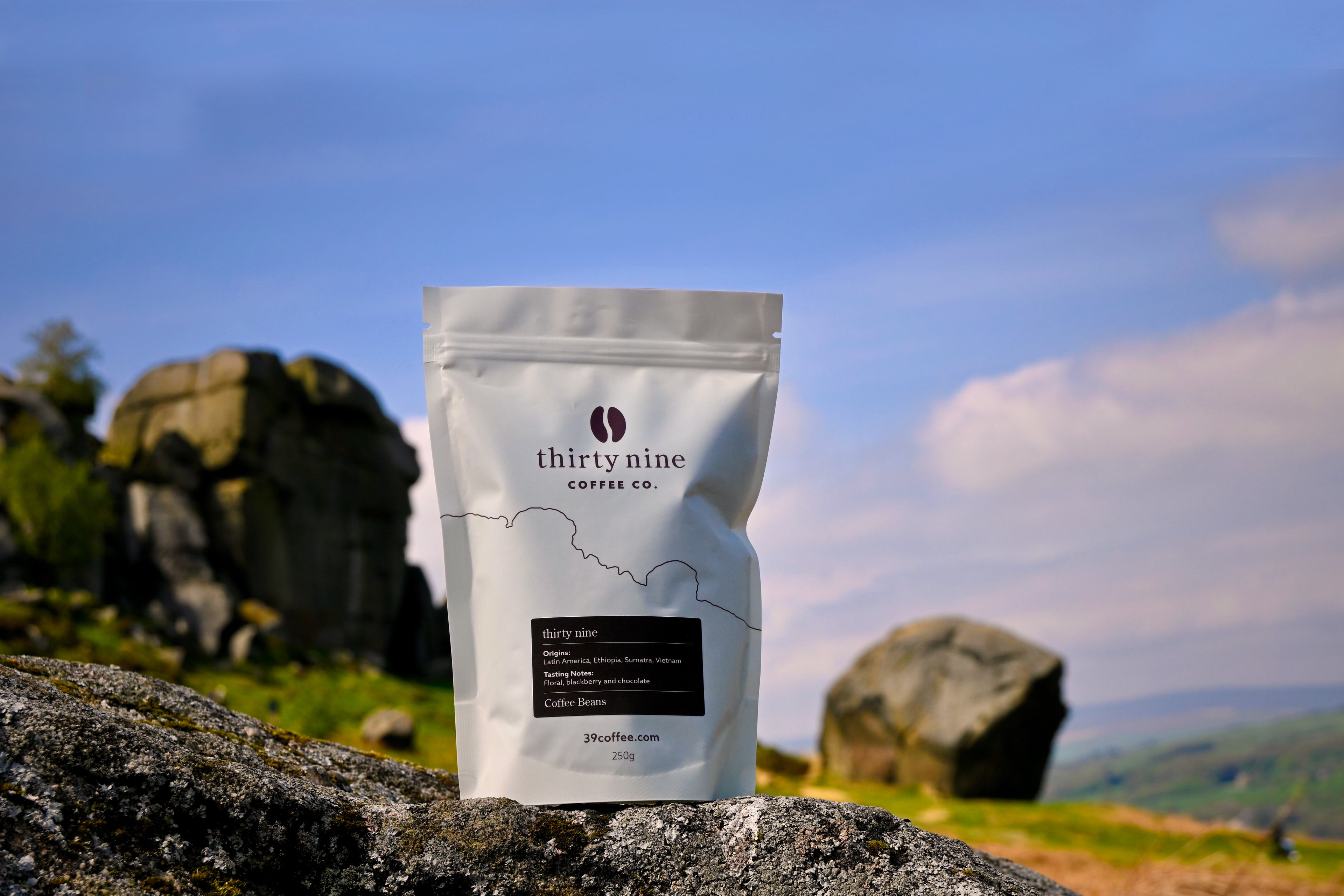 Coffee package with 'thirty nine coffee co.' branding on a rock with a scenic background
